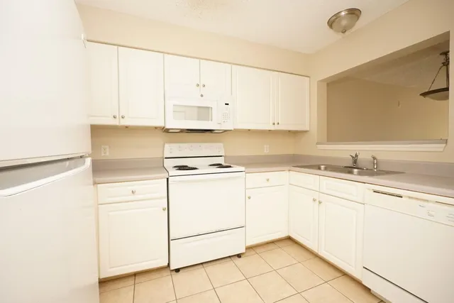 a kitchen with granite countertop white cabinets white appliances and sink