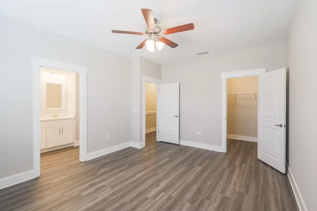 an empty room with wooden floor and a ceiling fan