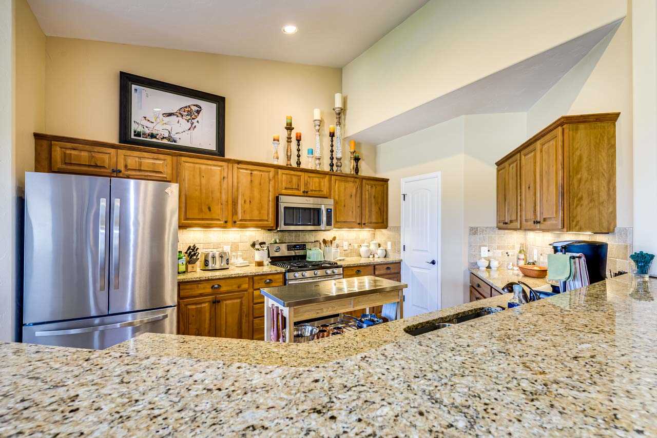 2530 Riata Ranch Court Grand Junction, CO 81505 - Photo 12 of 41 a kitchen with stainless steel appliances kitchen island granite countertop a refrigerator and a stove top oven