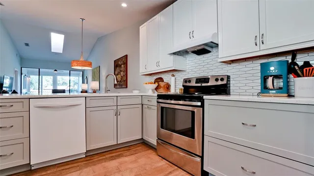 a kitchen with stainless steel appliances granite countertop a sink a stove and cabinets