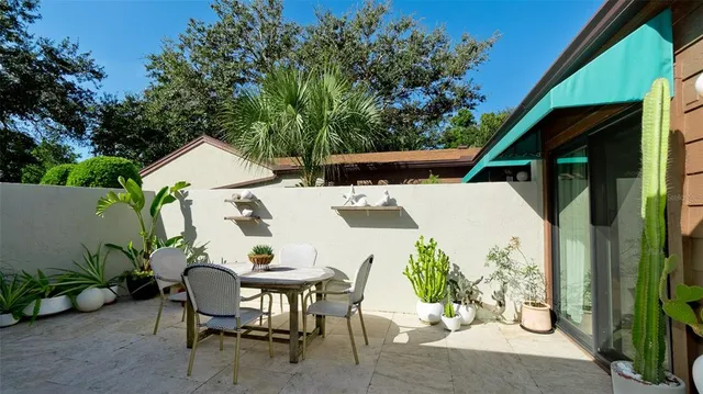 a view of a patio with table and chairs potted plants with wooden floor and fence