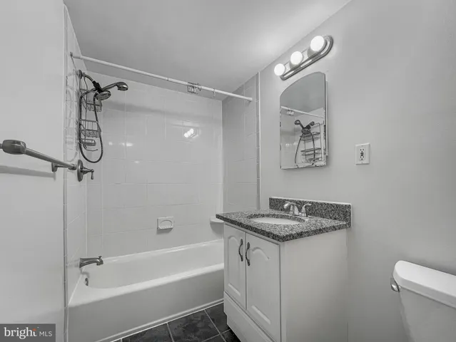 a bathroom with a granite countertop sink a toilet and shower