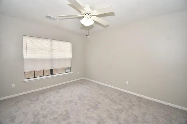 an empty room with a window and a fan