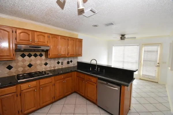 a kitchen with granite countertop a sink stove and cabinets