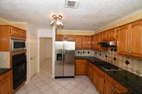 a kitchen with stainless steel appliances granite countertop a refrigerator a stove and a sink