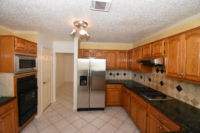 a kitchen with stainless steel appliances granite countertop a refrigerator a stove and a sink