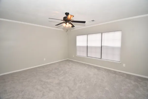 an empty room with windows and fan