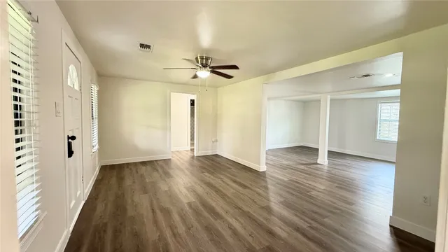 a view of an empty room with wooden floor and a window