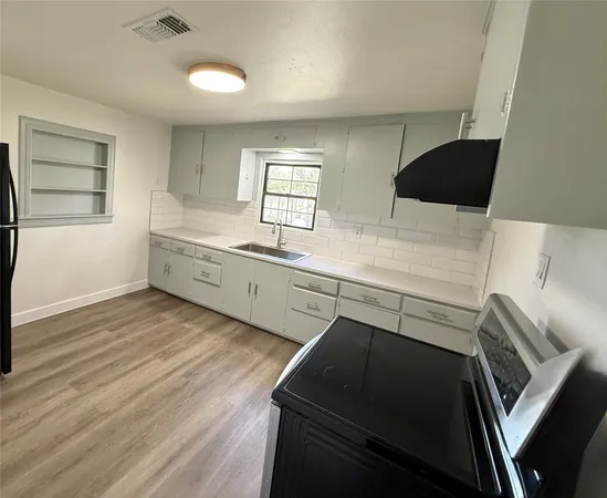 a kitchen with a sink and wooden floor