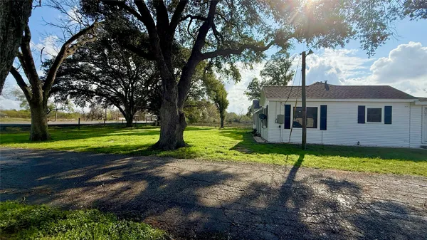 a view of a house with a big yard and large trees