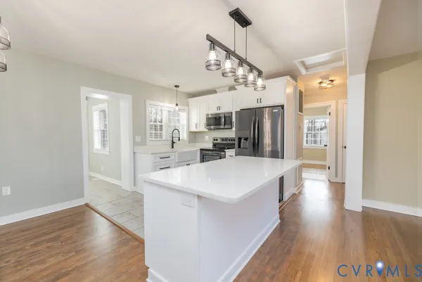 a large kitchen with a center island wooden floor stainless steel appliances and cabinets