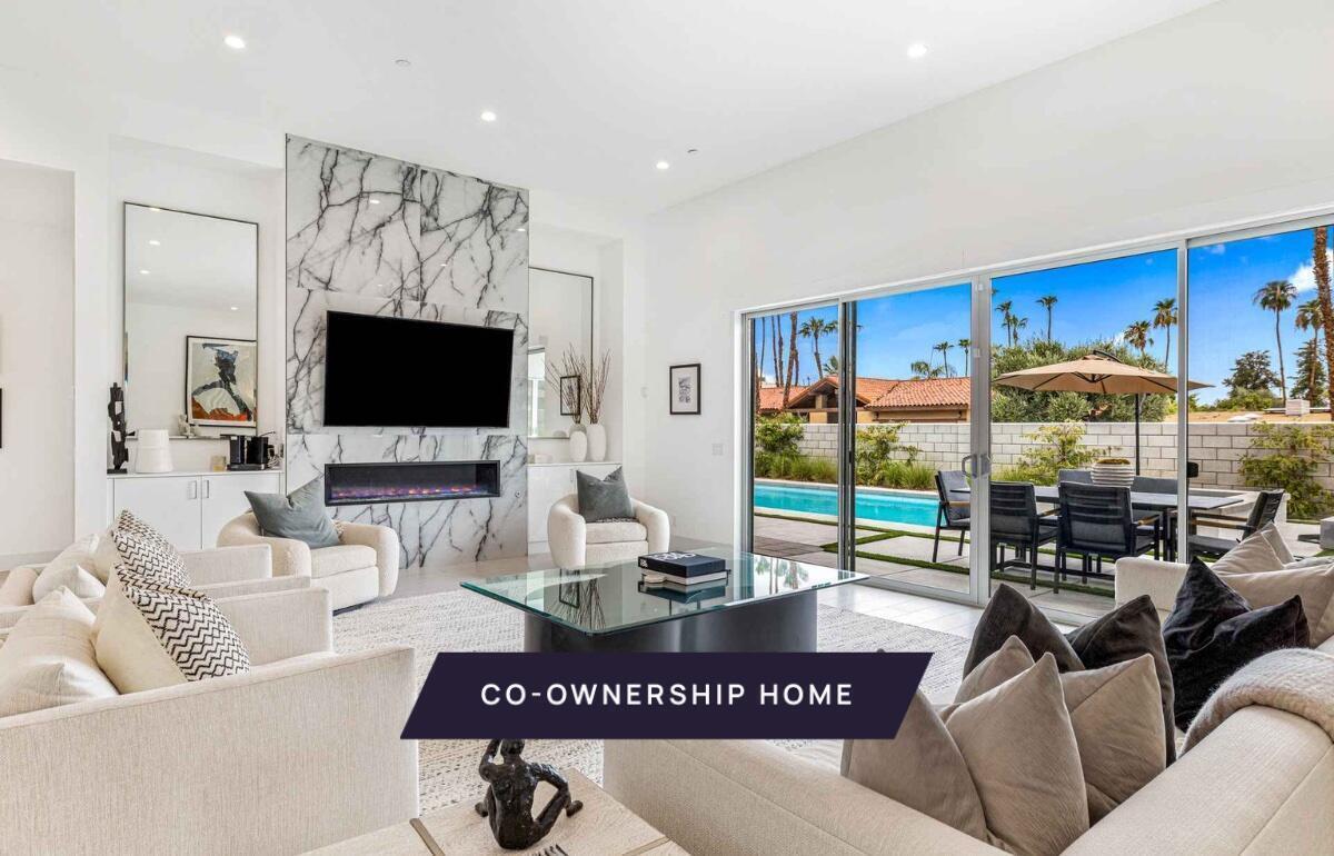 72985 Somera Road Palm Desert, CA 92260 - Photo 1 of 33 a living room with furniture a flat screen tv and a floor to ceiling window