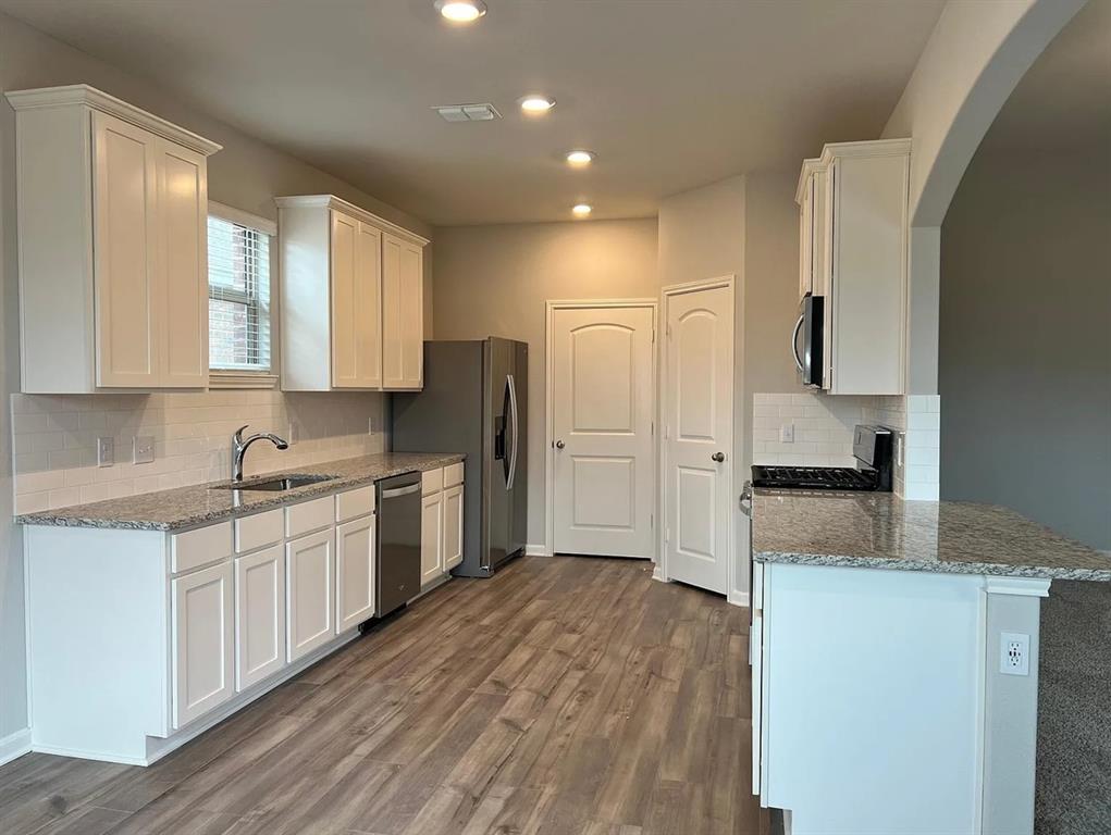 2013 Emma Court Anna, TX 75409 - Photo 4 of 20 Kitchen featuring wood-finish flooring, white cabinetry, speckled countertops, stainless steel appliances, and recessed lighting