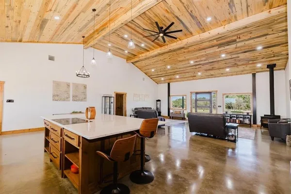 a kitchen with stainless steel appliances kitchen island granite countertop a table chairs sink and cabinets