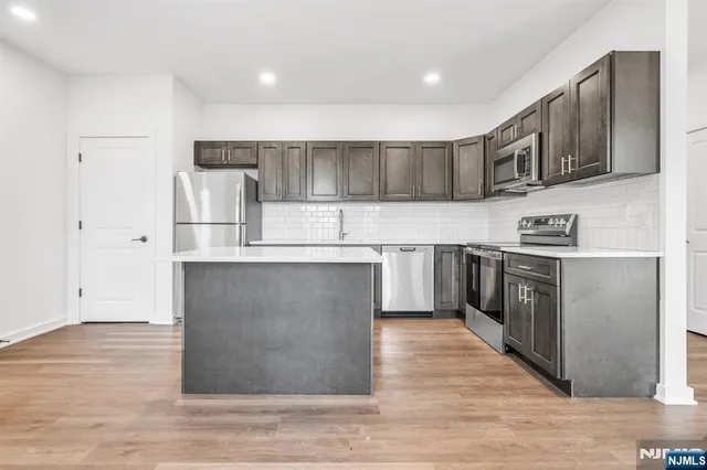 a kitchen with stainless steel appliances granite countertop a stove a sink and a refrigerator