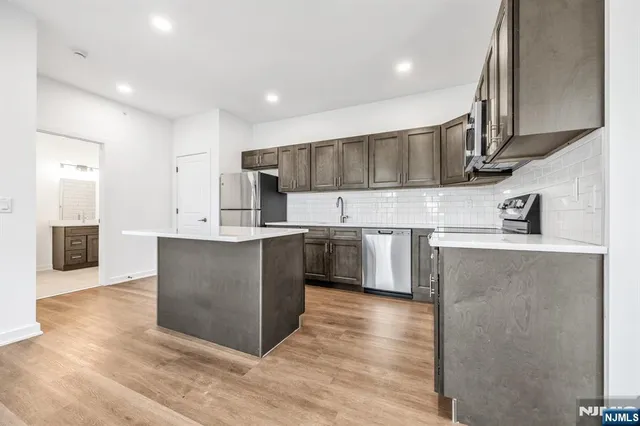 a kitchen with stainless steel appliances kitchen island granite countertop a refrigerator and a sink