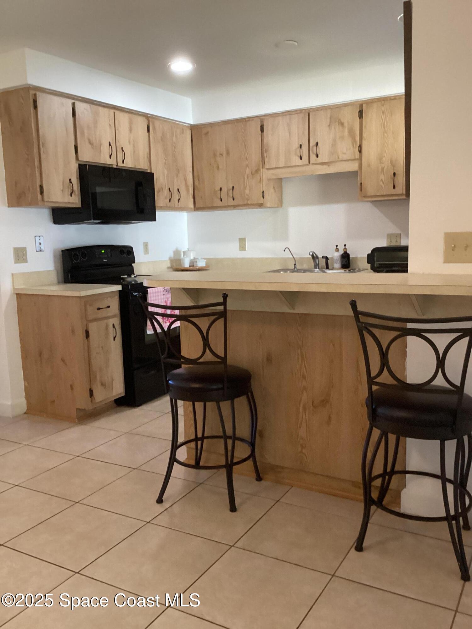2314 Manor Drive Northeast Palm Bay, FL 32905 - Photo 9 of 23 a kitchen with stainless steel appliances a stove a sink a stove a microwave and cabinets