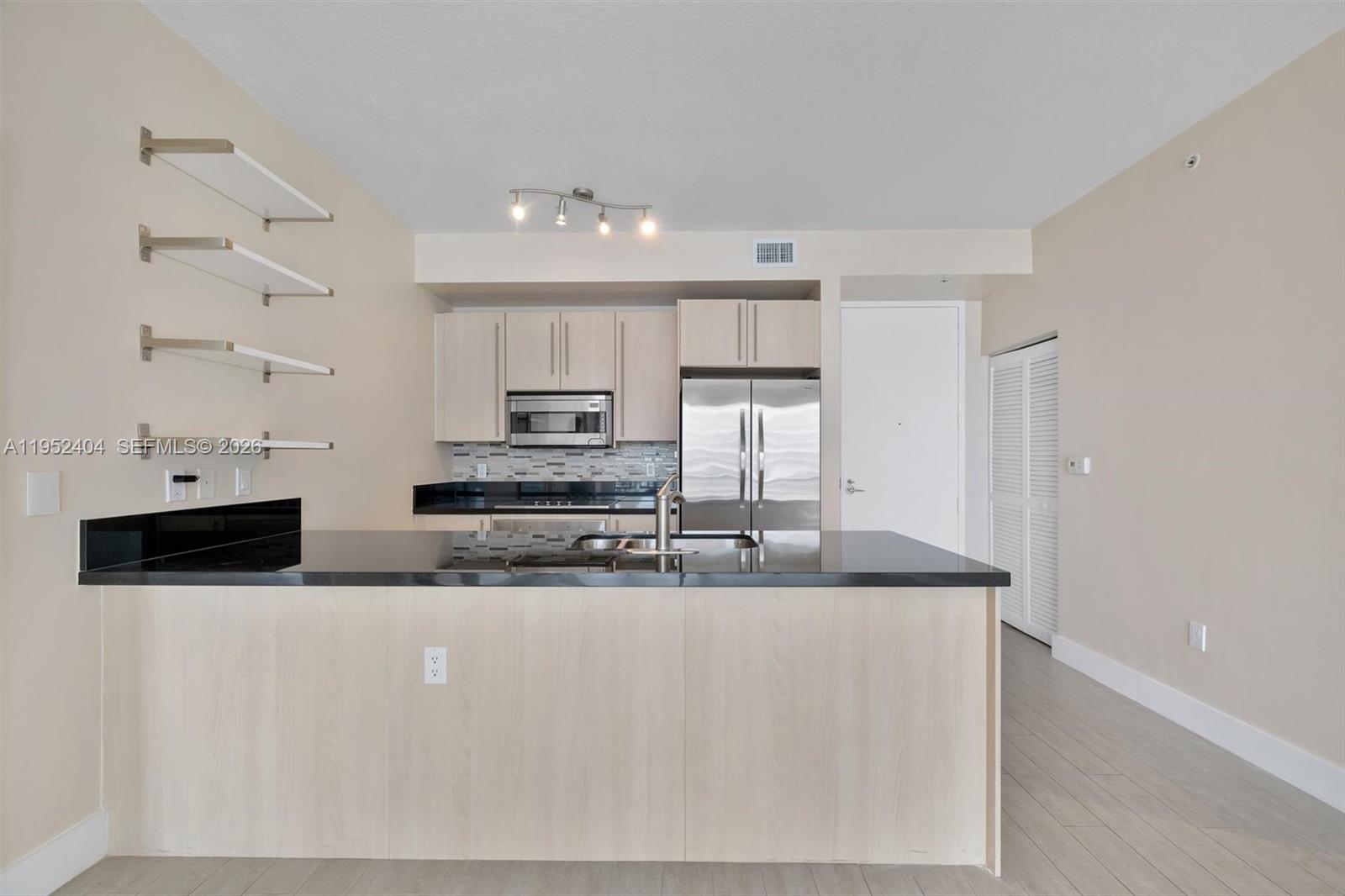 79 Southwest 12th Street, Unit 4004S Miami, FL 33130 - Photo 4 of 29 a large kitchen with stainless steel appliances a sink a stove a microwave and white cabinets