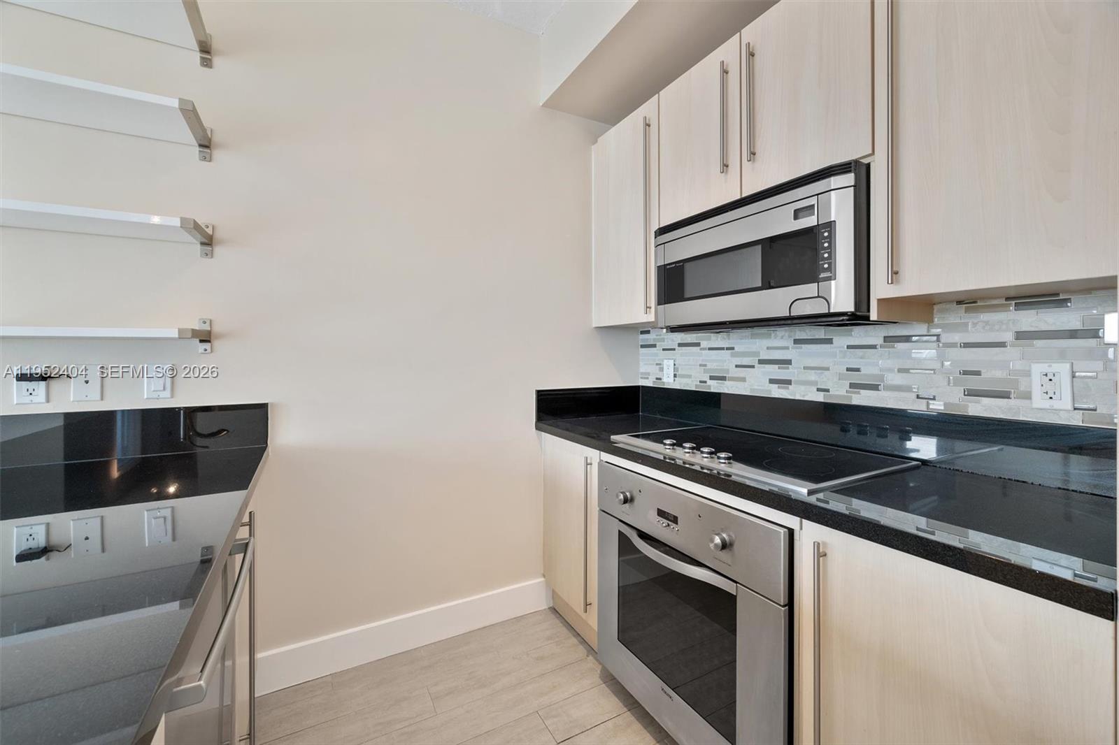 79 Southwest 12th Street, Unit 4004S Miami, FL 33130 - Photo 7 of 29 a kitchen with stainless steel appliances granite countertop a sink stove and microwave