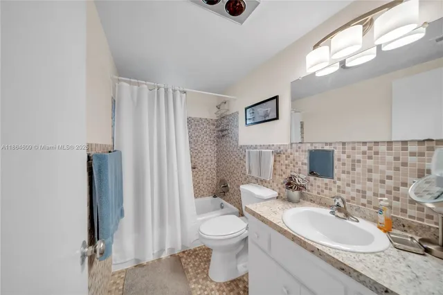 a bathroom with a granite countertop sink toilet a mirror and shower curtain