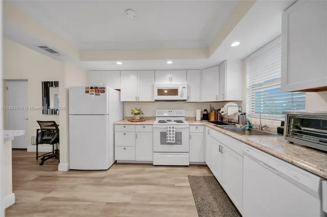 a kitchen with white cabinets and white appliances