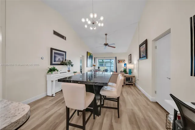 a dining room with wooden floor a chandelier a wooden table and chairs