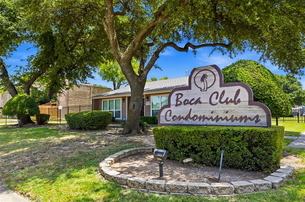 5540 Boca Raton Boulevard, Unit 181 Fort Worth, TX 76112 - Photo 21 of 21 "Boca Club Condominiums" signage with a stone-edged planter, surrounded by mature trees and manicured shrubbery, bordering a grassy area