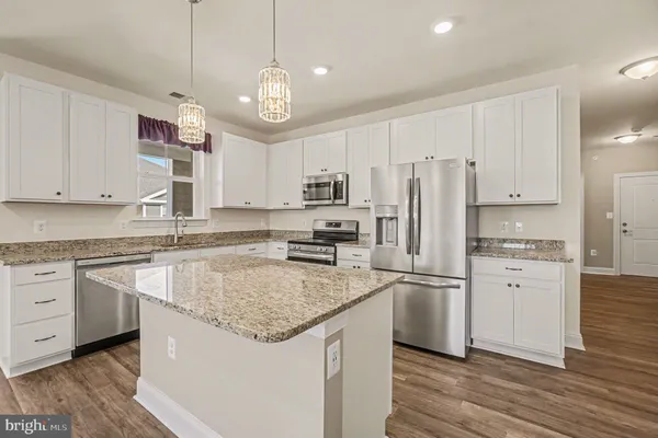 a large kitchen with kitchen island a stove a sink a center island and wooden floor