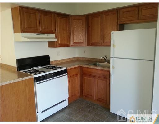 a white refrigerator freezer and a stove sitting inside of a kitchen with granite countertop wooden cabinets