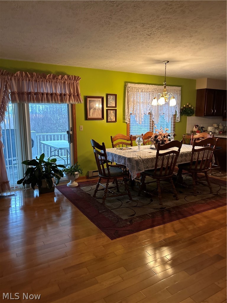 73323 Old Twenty One Road Kimbolton, OH 43749 - Photo 3 of 14 Dining area with a chandelier, a textured ceiling, and wood-type flooring