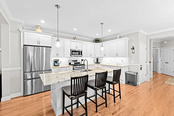 a large kitchen with kitchen island a large counter space wooden floor stainless steel appliances and cabinets