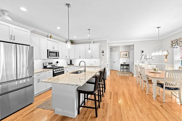 a dining room with wooden floor a chandelier a glass table and chairs