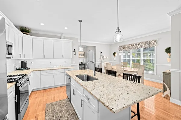 a kitchen with stainless steel appliances a dining table chairs refrigerator sink and cabinets