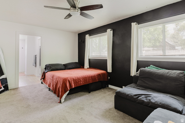 244 North 600 West Logan, UT 84321 - Photo 20 of 30 Carpeted room featuring a ceiling fan, two windows with blinds, a dark accent wall, and a doorway opening to an additional area