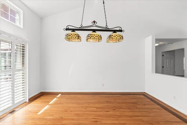 a view of an empty room with window and wooden floor