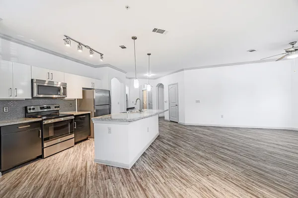 a large kitchen with a wooden floor and stainless steel appliances