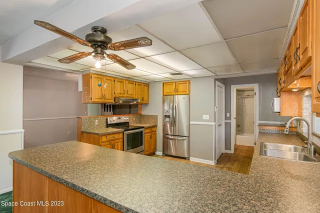 a kitchen with stainless steel appliances granite countertop a sink a stove top oven a chimney cabinets and a dining table