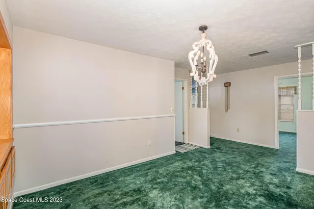 a view of a chandelier in big room with white walls
