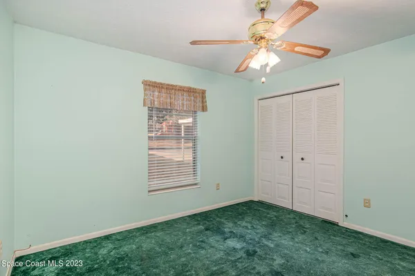 a view of an empty room with window chandelier fan