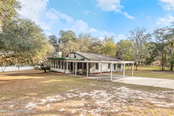 a view of a house with a big yard and large trees