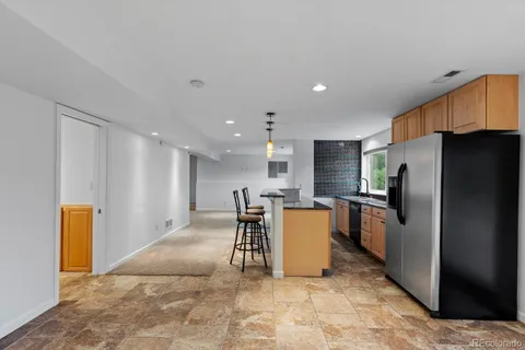 a large kitchen with stainless steel appliances kitchen island granite countertop a refrigerator and a stove top oven