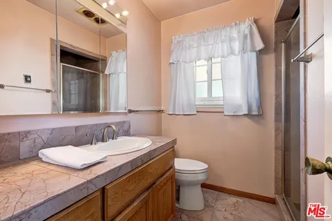 a bathroom with a granite countertop sink toilet and mirror