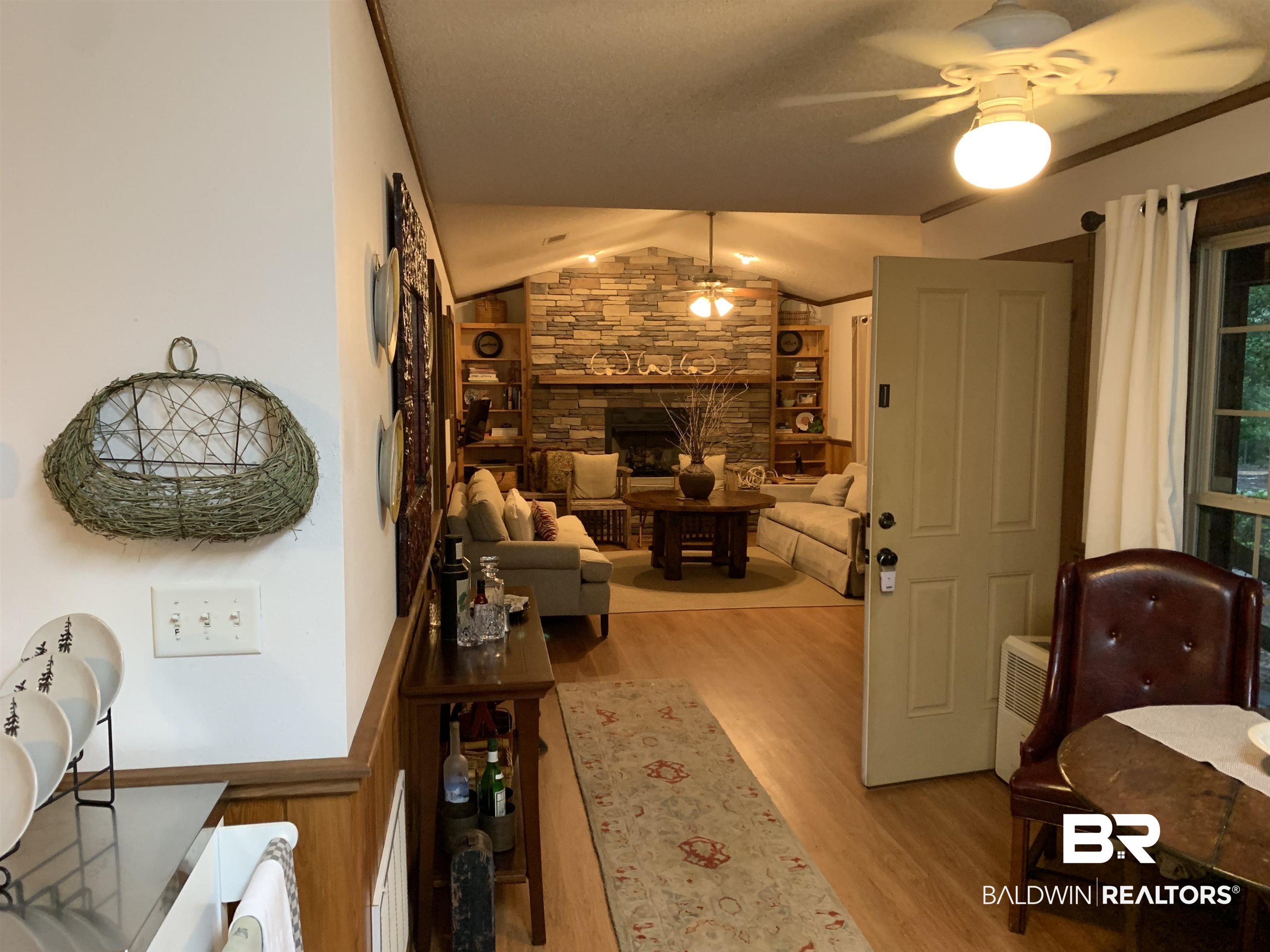 465 Rock Creek Road Wing, AL 36483 - Photo 5 of 15 Living room with vaulted ceiling, a stone fireplace, ceiling fan, and hardwood / wood-style floors
