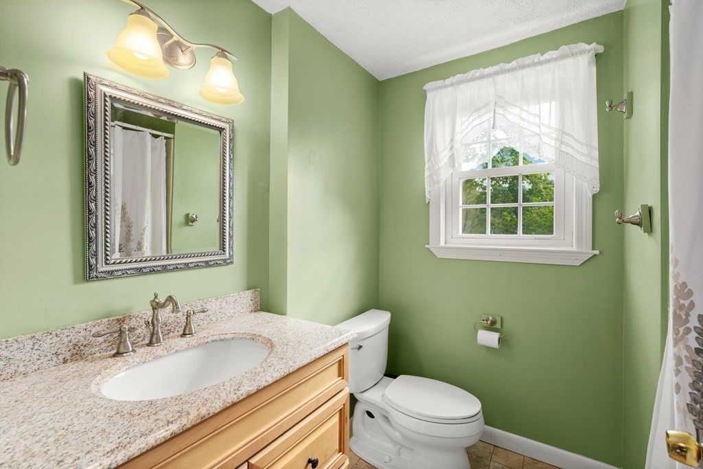 179 Baldwin Road Billerica, MA 01821 - Photo 16 of 38 a bathroom with a granite countertop toilet a sink and a mirror