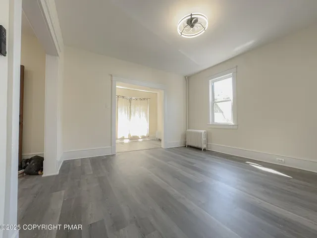 an empty room with wooden floor and window