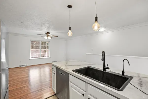 a kitchen with stainless steel appliances granite countertop a sink a window and wooden floor