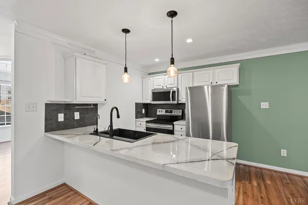 a kitchen with stainless steel appliances a refrigerator a stove a sink and a wooden floor