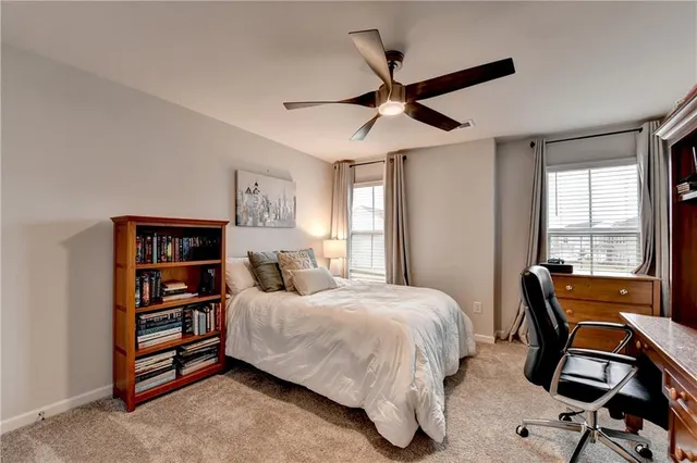 a bedroom with a bed a computer on the desk and a book shelf