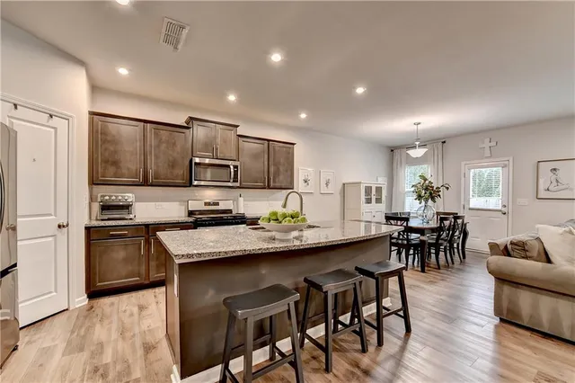a kitchen with stainless steel appliances granite countertop a table chairs refrigerator and sink