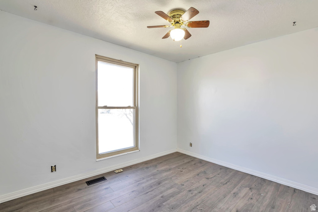1057 North 700 West Clinton, UT 84015 - Photo 8 of 15 Empty room featuring dark wood-style flooring, a textured ceiling, and ceiling fan